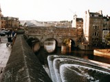 Pulteney Bridge is a bridge over the River Avon in Bath, England. It was completed by 1774, and connected the city with the land of the Pulteney family which the family wished to develop. Designed by Robert Adam in a Palladian style, it is highly unusual in that it has shops built across its full span on both sides.